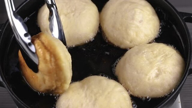 cooking berliners or doughnuts on a frying pan, top view. fat and oil boiling, hot temperature