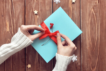 A woman packs a holiday gift in a blue box