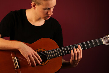 Obraz premium Young man playing classic acoustic guitar