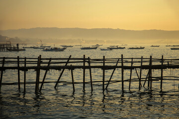 Sunrise view from sea with beautiful twilight sky, fishing boats preparing the trap with mountain in background.