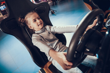 Girl smiles while driving a game car. 