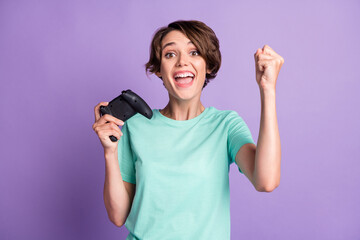 Photo of lucky winner young woman dressed casual turquoise clothes playing gamepad isolated violet color background