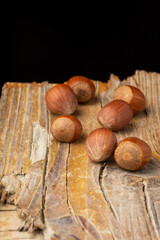 Top view of hazelnuts on rustic wooden table, with selective focus, black background, in vertical, with copy space