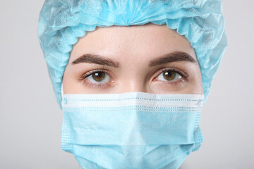 Young woman doctor in a protective mask on a light background