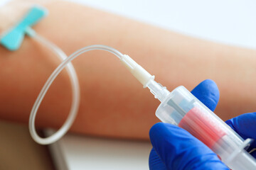Hands of a doctor taking blood samples using a tube holder