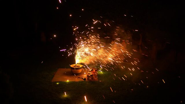 Fireworks in plant pot in yard smoke with bright clors and cracking sparks