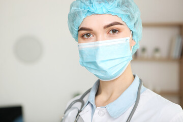 young girl doctor in a medical mask in the interior of the office