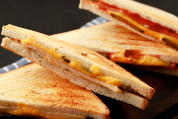 Sandwiches cut into halves on wooden cutting board with napkin