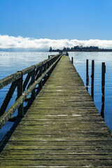 Obraz premium An old weathered wharf sticking far out into the waters of a lake. The historic Tokaanu Wharf on Lake Taupo, New Zealand