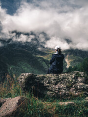 girl sitting on a rock against the background of mountains and clouds
