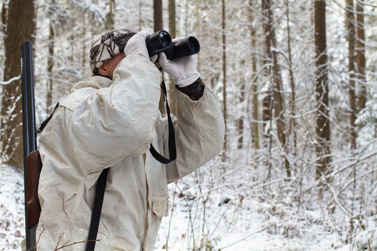 hunter in winter forest with binoculars
