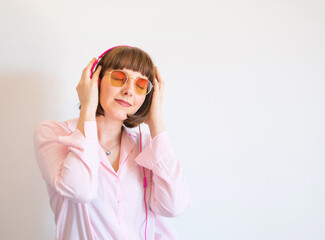 Young happy woman in pink shirt with headphones engrossed in listening to the music.