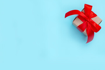Gift box with a red bow on a pastel blue background. Minimal festive composition. Copy space for text.