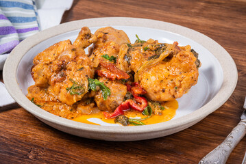 Ready Italian dish - Tuscan chicken with sun-dried tomatoes, tomato paste, spinach, cream and cheese on a plate on a wooden table