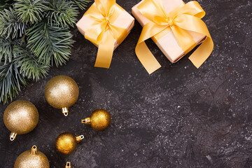 Fototapeta na wymiar Beautiful golden Christmas balls, gifts with a gold bow and a fir branch on a dark black background. Flat design. Copy space.