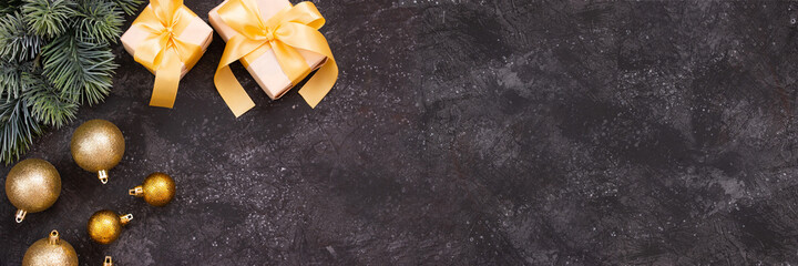 Beautiful golden Christmas balls, gifts with a gold bow and a fir branch on a dark black background. Flat design. Copy space.