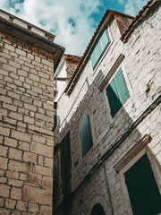 old stone houses with green wooden shutters in the old town of trogir during summer vacation in croatia