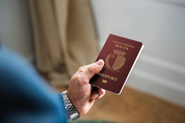 Business Man in a suit is holding malta passport in left hand - obrazy, fototapety, plakaty