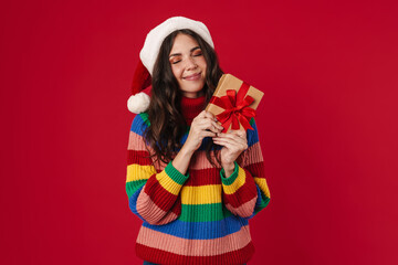 Beautiful happy girl in Santa Claus hat posing with Christmas gift