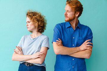 Redhead resentful couple having argument while posing with arms crossed