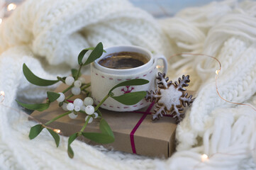 white knitted scarf, gift box, cup of coffee, mistletoe branches, gingerbread cookie. romantic breakfast.