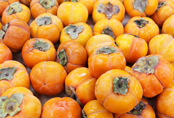 Ripe orange persimmons. on the table in the market. A bunch of organic persimmon fruits at a local farmers market. Persimmon background. Flat lay. Copy space for text and content.