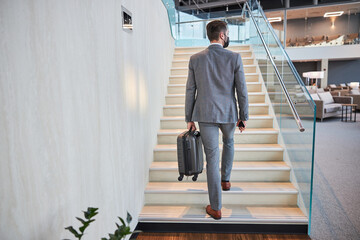 Business executive climbing the stairs with his carry-on