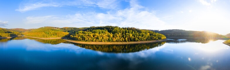 Fototapeta na wymiar a lake in an sunny autumn landscape reflection panorama