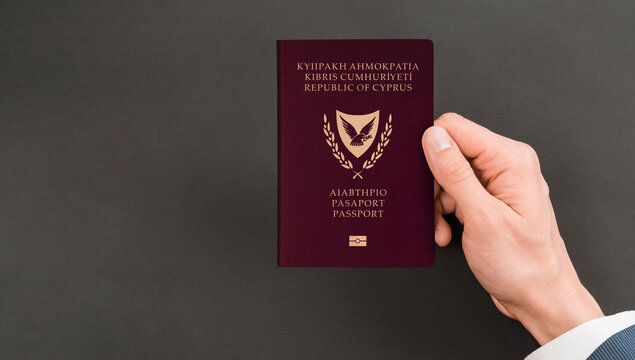 Hand holding Cypriot passport with black background, space for texts