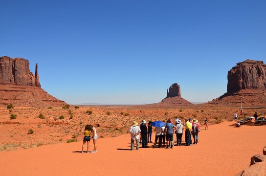 Monument Valley in Arizona, group of tourists are taking photos, noon blue sky, sunny, heat