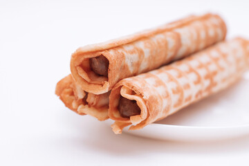 Waffles tubes with condensed milk on white plate