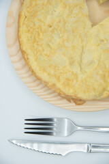 tortilla de patata sobre un plato de madera y fondo blanco