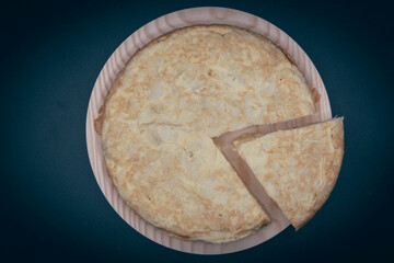 Tortilla de patata cortada en un plato de madera con fondo negro