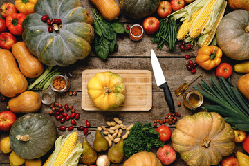 Wooden cutting board with autumn vegetables on wooden table
