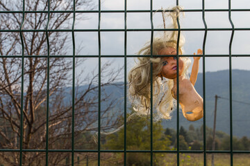 An old broken doll hangs on the fence. Bosnia and Herzegovina