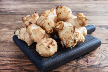 Raw Jerusalem artichoke, topinambur tubers on a rustic wooden background. Copy space.