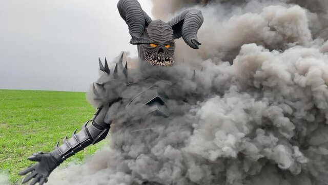 Mutant warrior walks with glowing eyes against a background of black smoke.