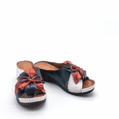 Women's casual summer shoes. Open mules made of genuine leather with a thick sole. The color is blue-red-white. Decoration - bow. Isolated over white background.