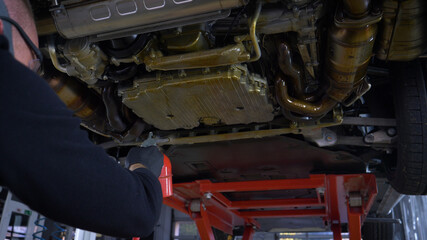 A man in a car service blows out the lower part of the car body. Protective coating of the lower part of the car body.