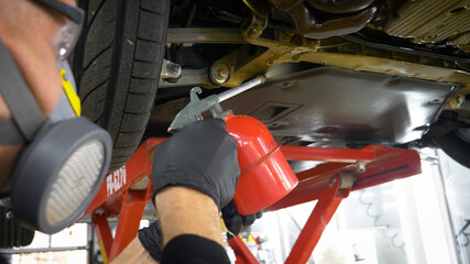 A man in a car service blows out the lower part of the car body. Protective coating of the lower part of the car body.