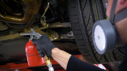 A man in a car service blows out the lower part of the car body. Protective coating of the lower part of the car body.
