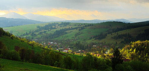 Spring morning rural landscape in the Carpathian mountains. Dramatic sky before dawn, ray of sun trying to break through the clouds.