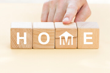 Businessman hand arranging wood block stacking with home icon. Business to house real estate concept.