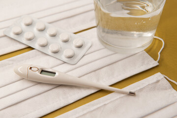 Virus protection mask, thermometer, tablets on a colored background. Symbolize protection and treatment from diseases and viruses