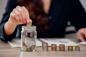 Close up Businesswoman Hand holding coins putting in glass. concept saving money for finance accounting