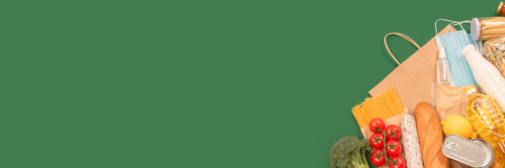 Banner with food and medicines donations on green background with copyspace - pasta, fresh vegatables, canned food, baguette, cooking oil. Food bank concept. Flat lay, selective focus