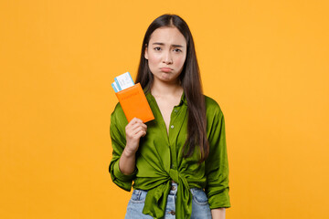 Upset traveler tourist asian woman in green shirt hold passport tickets isolated on yellow background, studio portrait. Passenger traveling abroad on weekends getaway. Air flight journey concept.