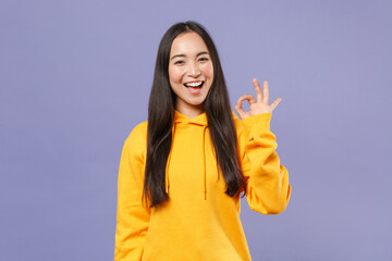 Cheerful laughing beautiful young brunette asian woman 20s wearing basic casual yellow hoodie...