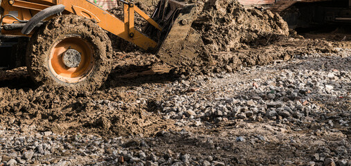 Muddy wheels of an excavator bulldozer truck working on a construction site