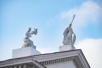 Fototapeta premium White statues on the roof of a house against a clear sky